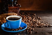 cup of coffee with coffee beans and grinder background