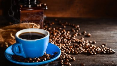 cup of coffee with coffee beans and grinder background