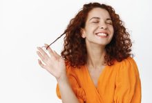 cuidados com a pele da beleza retrato de uma jovem natural com cabelo ruivo encaracolado rindo feliz dentes de sorriso branco brincando com o cabelo em pe despreocupado contra o fundo branco